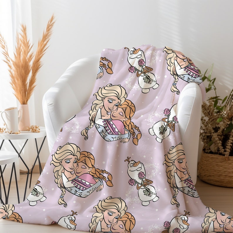 Pu&ograve; includere: Una coperta in pile rosa con un motivo ripetuto di due sorelle che si abbracciano e un pupazzo di neve che tiene una rosa. Le sorelle hanno i capelli lunghi e biondi e indossano abiti blu e rosa. Il pupazzo di neve &egrave; bianco con un naso di carota e occhi neri.