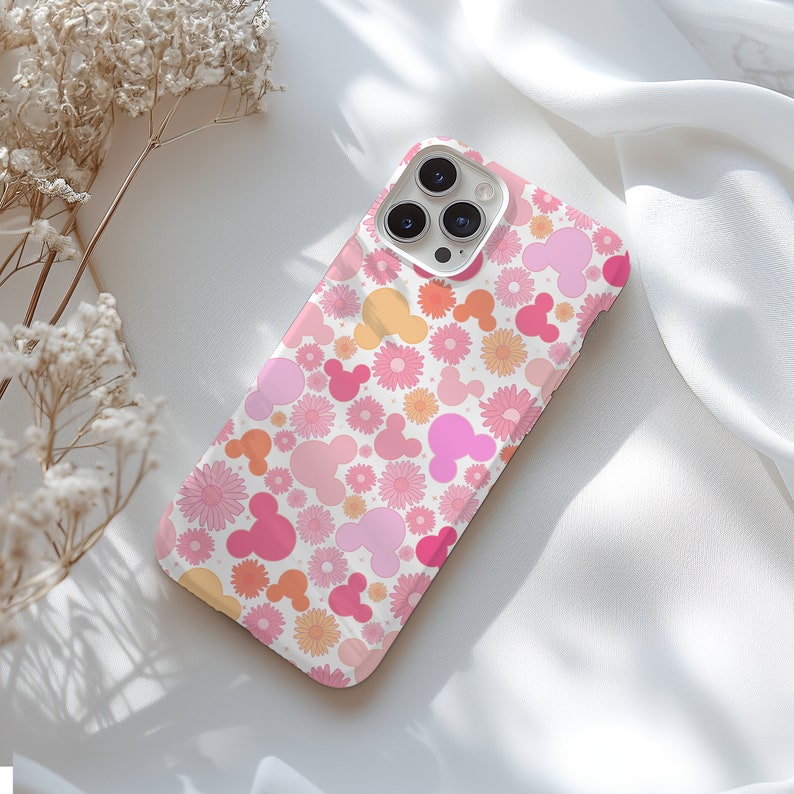 May include: A white iPhone case with a pink and orange floral pattern featuring Mickey Mouse ears.