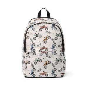 Può includere: Uno zaino color crema con una stampa all-over di moto da cross in vari colori, tra cui rosso, blu e verde, intervallate da piccole bandiere a scacchi nere e icone a forma di stella. La borsa presenta una maniglia superiore e cerniere nere.