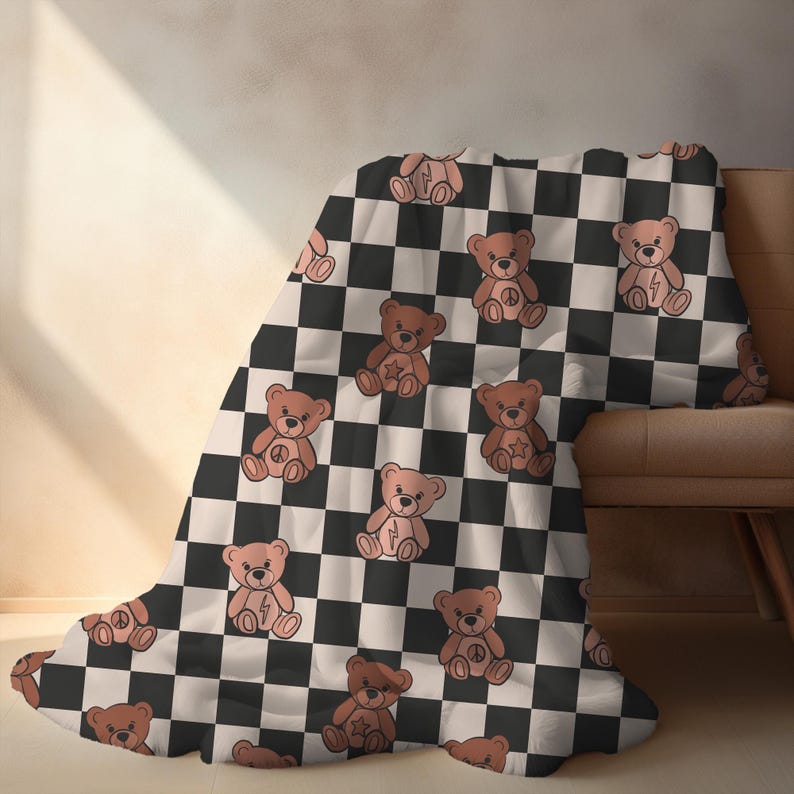 Pu&ograve; includere: Una coperta a quadri bianchi e neri con un motivo ripetuto di orsacchiotti marroni che indossano simboli di pace. La coperta &egrave; morbida e accogliente, perfetta per coccolarsi sul divano.