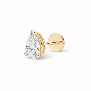 May include: A single gold stud earring featuring a pear-shaped, clear diamond. The diamond is set in a gold bezel setting. The earring post and backing are also gold. The earring is shown against a white background.