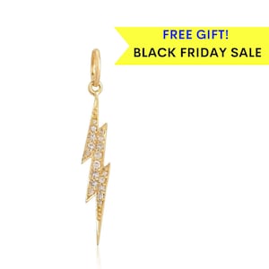 May include: A gold lightning bolt charm with clear cubic zirconia stones. The charm is on a white background.