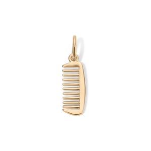 Puede incluir: Un colgante de peine de color dorado con un lazo para un collar o pulsera. El peine tiene una forma curvada con dientes espaciados uniformemente. El colgante es probablemente de metal y se muestra sobre un fondo blanco.