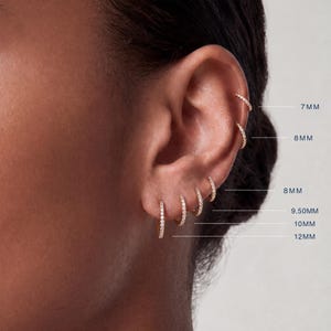 May include: A set of six gold hoop earrings with embedded clear stones, arranged in a vertical line along the ear. The hoops are labeled with sizes 7mm, 8mm, 8mm, 9.50mm, 10mm, and 12mm, indicating their respective diameters in millimeters.