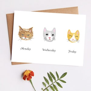 May include: A white card with three watercolor illustrations of cats. The first cat is brown and orange with a grumpy expression and is labeled "Monday". The second cat is gray and white with a neutral expression and is labeled "Wednesday". The third cat is orange with a happy expression and is labeled "Friday".