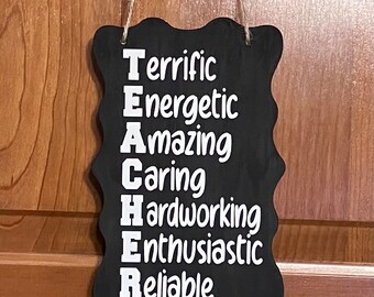 May include: Black chalkboard sign with white text that reads "TEACHER" with each letter representing a positive adjective: "Terrific, Energetic, Amazing, Caring, Hardworking, Enthusiastic, Reliable".