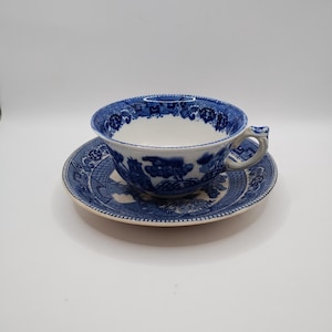 May include: A blue and white teacup and saucer set with a willow pattern design.