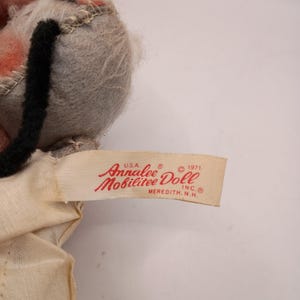 May include: A vintage Annalee Mobilitee Doll, featuring a gray head with pink ears and a black tail. The doll's tag reads "Annalee Doll, Meredith, N.H., USA, 1971". The doll is made of felt and fabric.