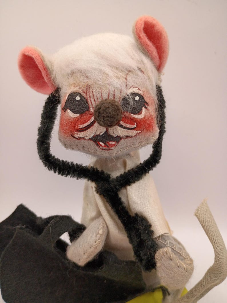 May include: A vintage handmade mouse doll with a white head, pink ears, and a brown nose. The mouse wears a white shirt and has a black stethoscope around its neck. The doll has a black cape and a long, curved tail.