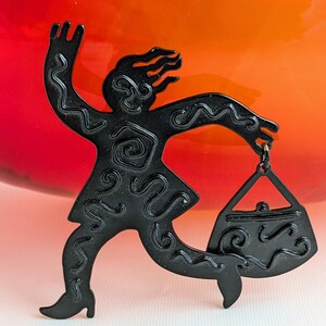 May include: Black metal silhouette of a person running with a purse. The person is stylized with wavy lines and the purse has a detailed design.