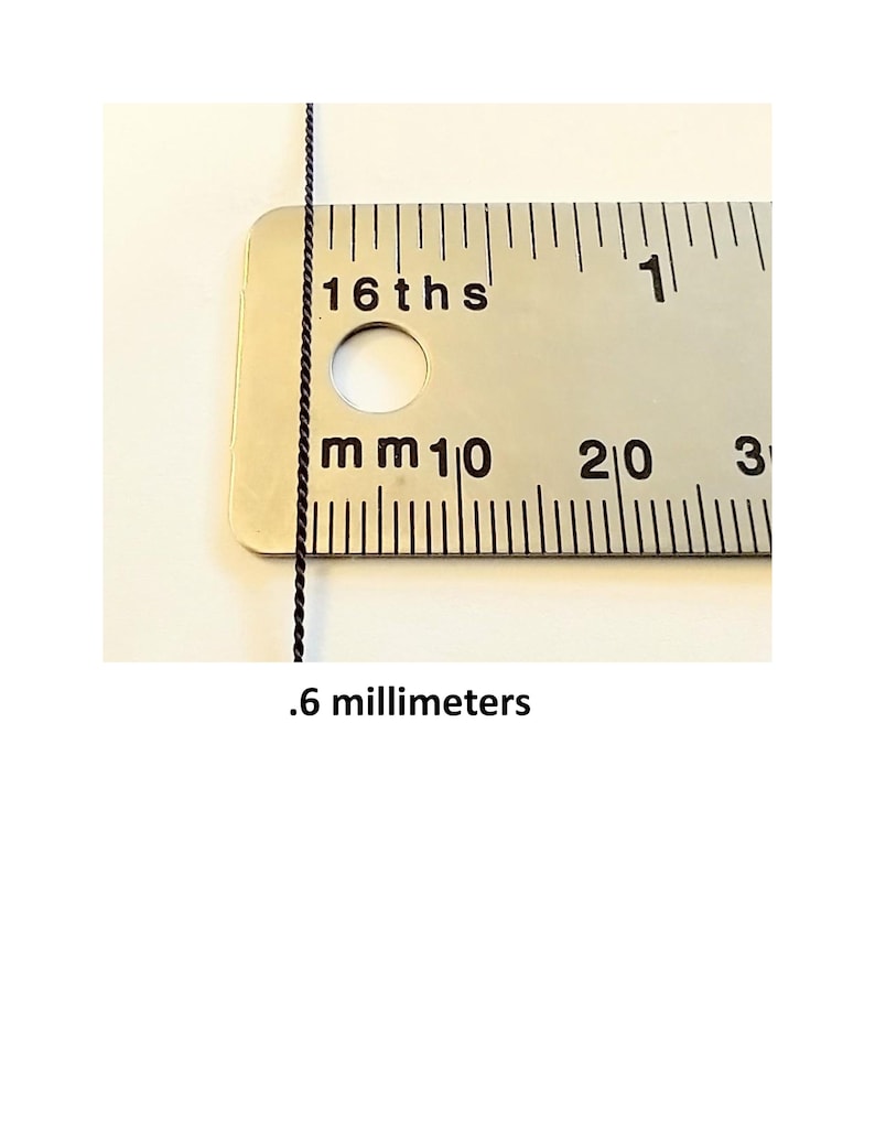 May include: A thin black twisted cord positioned vertically against a metal ruler. The ruler displays markings for 16ths of an inch and millimeters. The text .6 millimeters is printed below the cord, indicating its measured diameter.