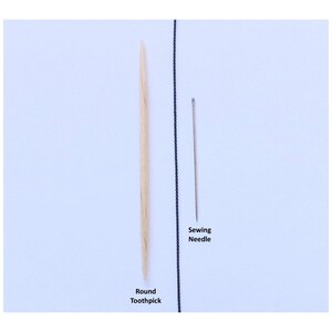 May include: A light-colored wooden round toothpick positioned vertically next to a thin silver-colored metal sewing needle. A thin black vertical line separates the two items. The text Round Toothpick and Sewing Needle is printed below them.
