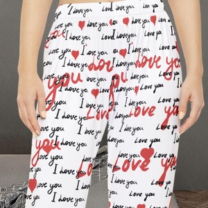 Peut inclure: Un pantalon de pyjama blanc avec un motif répété de "I love you" en écriture rouge et de petits cœurs rouges. Le pantalon est fait d'une matière douce et possède une taille élastique. Parfait pour se détendre.