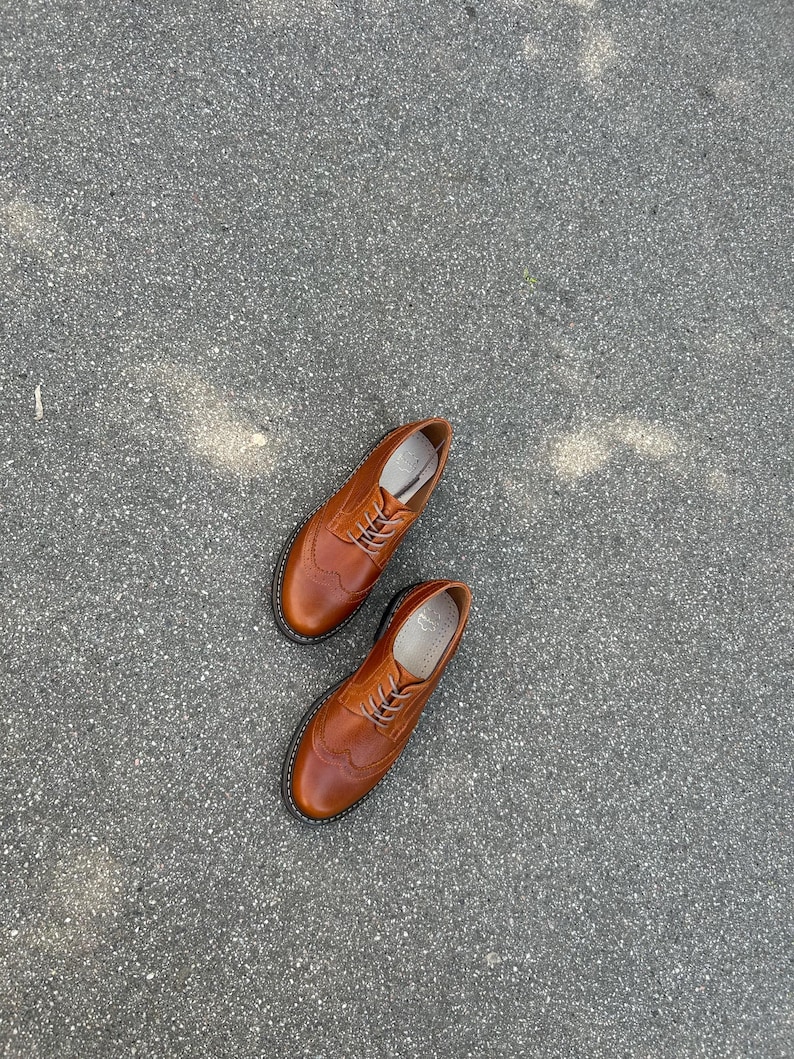 Pu&ograve; includere: Un paio di scarpe brogue in pelle marrone con dettagli intricati e un design classico. Le scarpe hanno una punta arrotondata, una chiusura con lacci e una suola nera. Le scarpe misurano circa 28 cm di lunghezza.