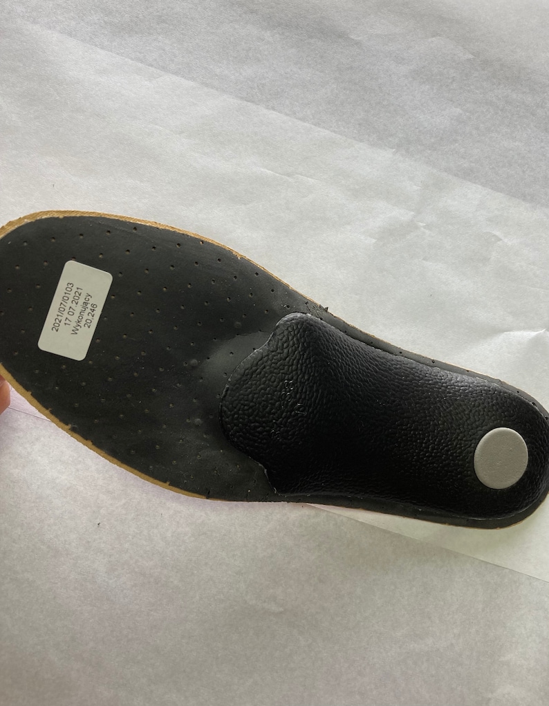 May include: Black insole with a gray circle on the heel. The insole has a label that reads "2021/07/0103 17.07.2021 Wykonawcy 20.248"