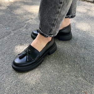 May include: Black leather loafers with a tassel detail and a chunky platform sole.