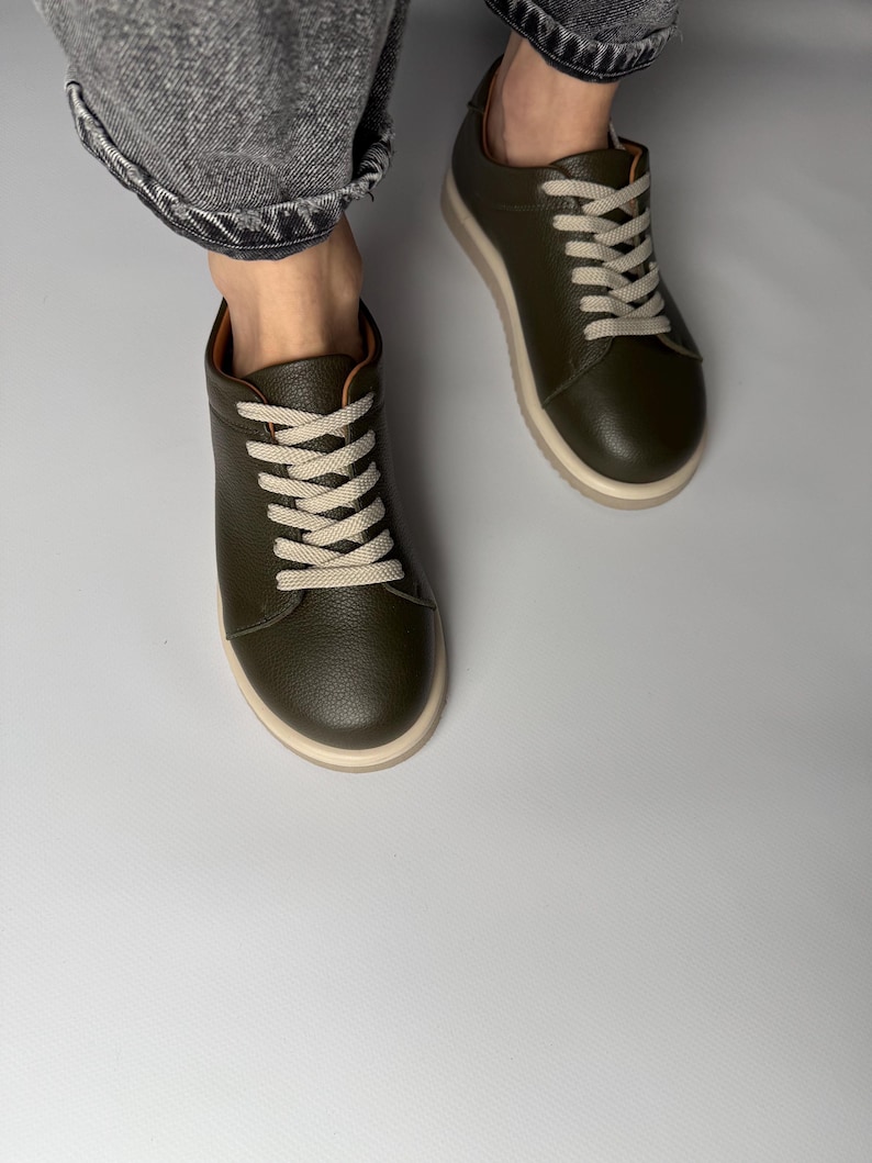 May include: A pair of green leather low-top sneakers with white laces. The sneakers have a white rubber sole.