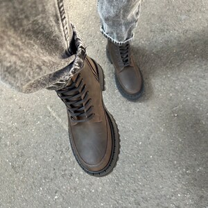 May include: Brown leather lace-up boots with a chunky black rubber sole.