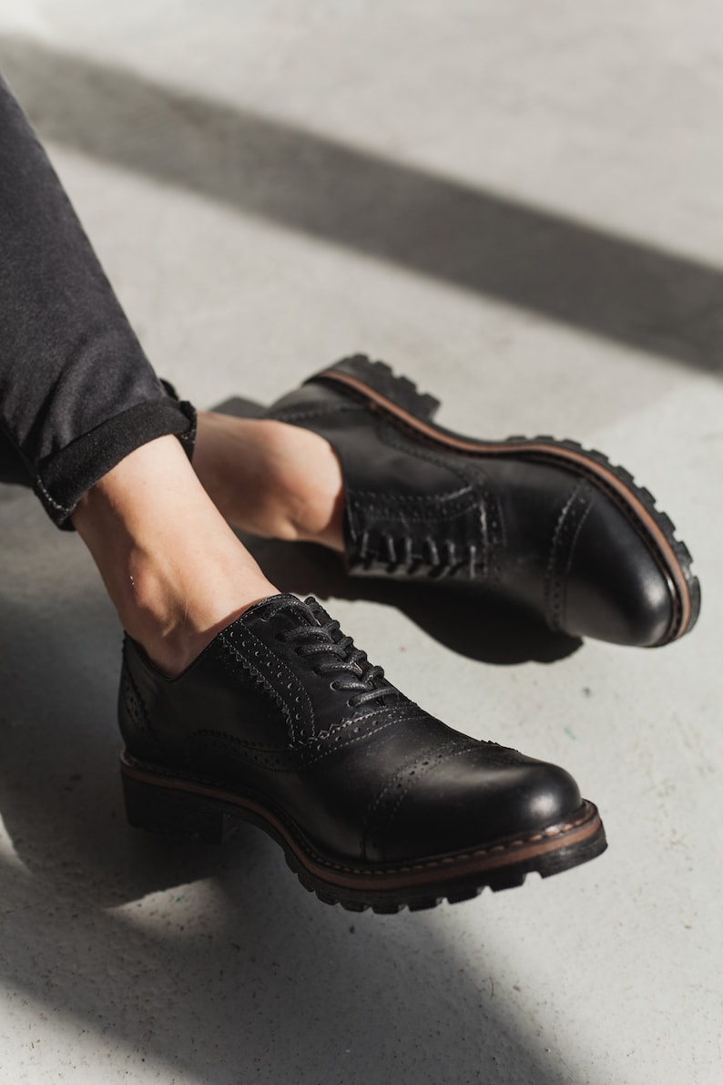 May include: A pair of black leather lace-up shoes with a brogue design and a thick sole.