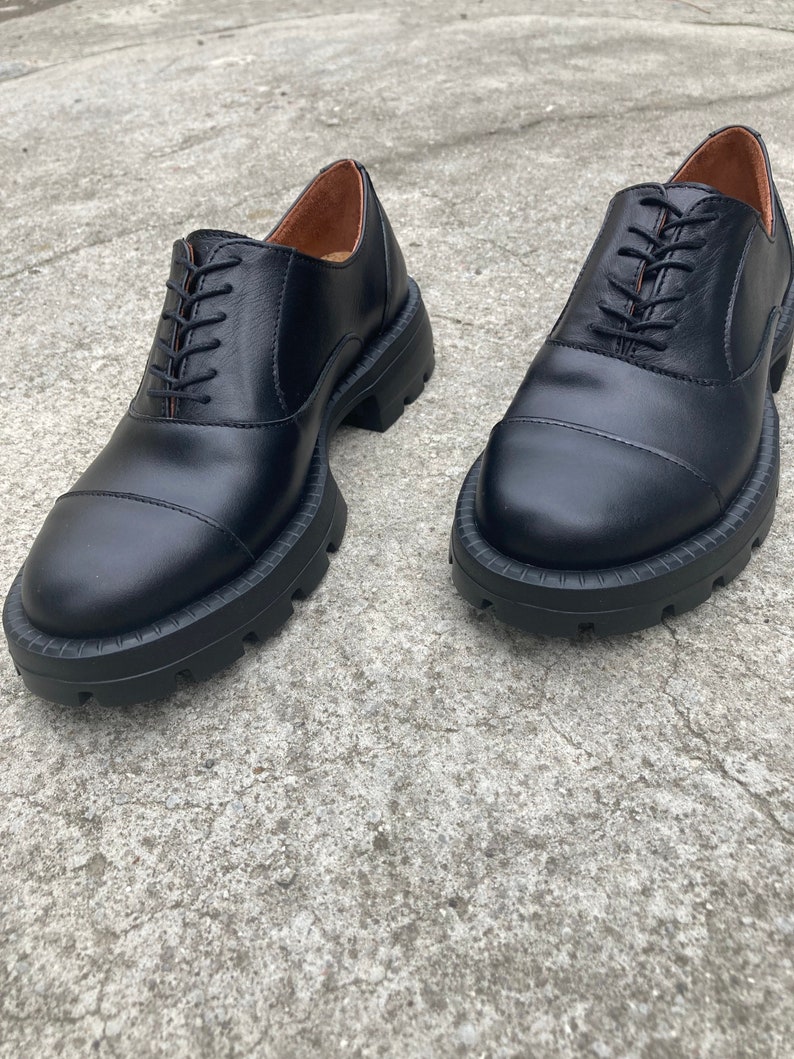 May include: A pair of black leather lace-up shoes with a chunky rubber sole.