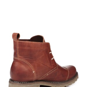 May include: Brown leather ankle boots with laces. The boots have a rugged sole and a slightly pointed toe.