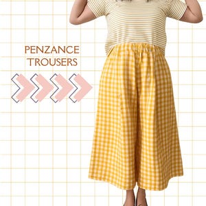 May include: A woman wearing a yellow and white striped t-shirt and yellow gingham trousers. The trousers have a wide leg and are paired with dark blue flats. The text "PENZANCE TROUSERS" is visible on the left side of the image.