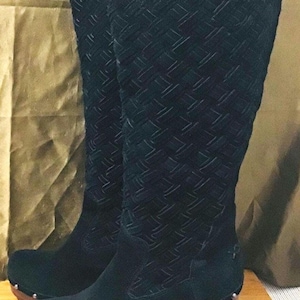 Könnte beinhalten: Schwarze, kniehohe Stiefel aus Wildleder mit gewebtem Muster und einem Holzabsatz. Der Absatz hat Metallnieten.