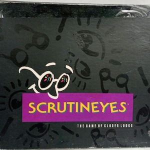 May include: A black box game with the title "ScrutinEyes: The Game of Closer Looks" in white text on a purple banner. The box is decorated with black and white drawings of eyes and glasses.