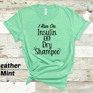 Puede incluir: Una camiseta verde menta jaspeada con el texto "I Run On Insulin And Dry Shampoo" impreso en negro.