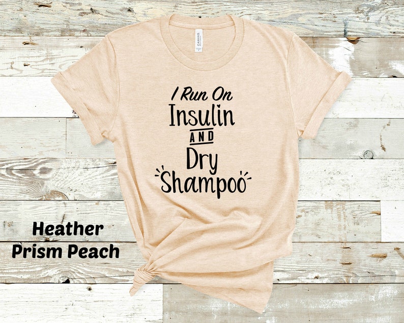Puede incluir: Una camiseta beige con el texto "I Run On Insulin And Dry Shampoo" impreso en negro.