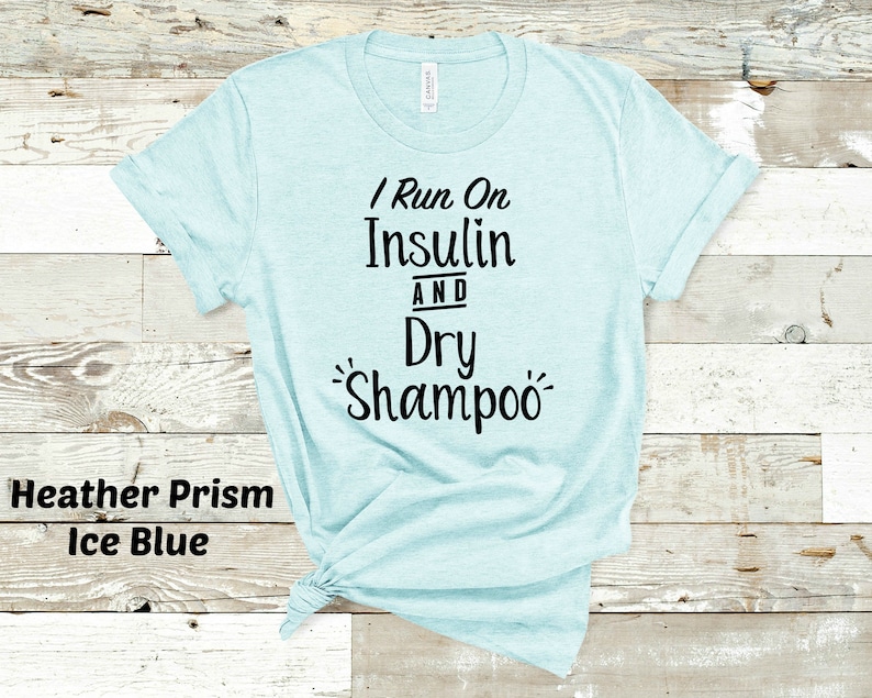 Puede incluir: Una camiseta azul claro con el texto "I Run On Insulin And Dry Shampoo" impreso en negro.