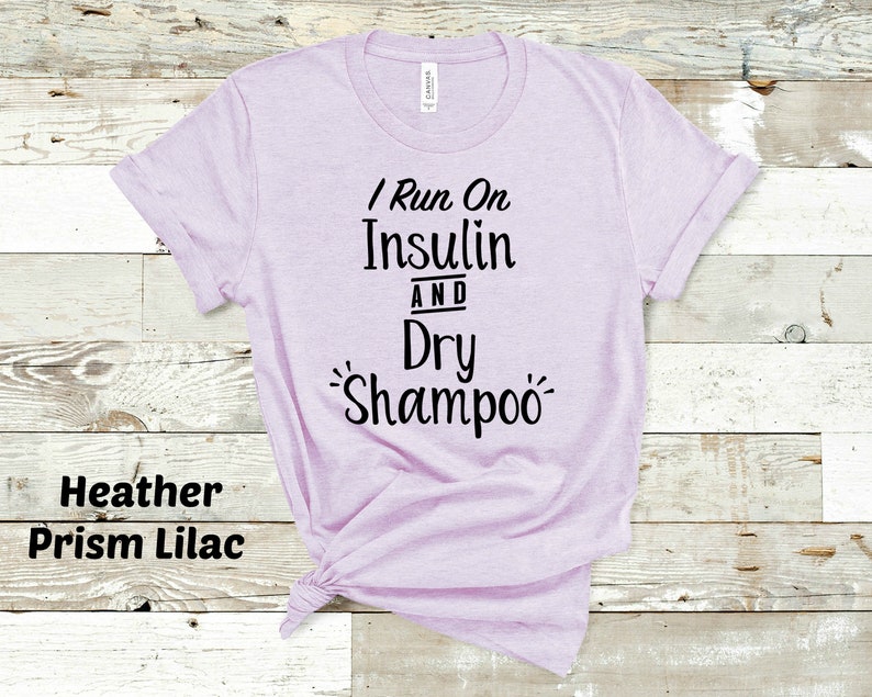 Puede incluir: Una camiseta de color lila prisma heather con el texto "I Run On Insulin And Dry Shampoo" impreso en negro.