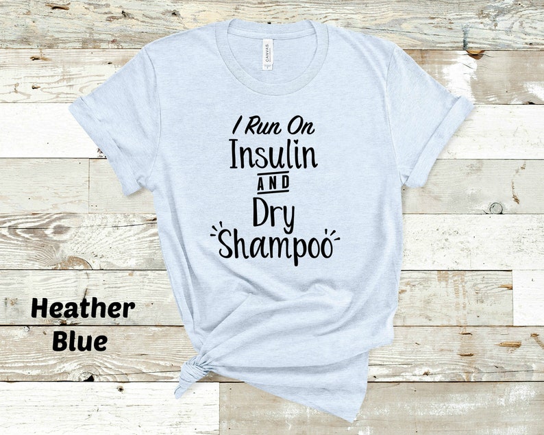 Puede incluir: Una camiseta azul claro con el texto "I Run On Insulin And Dry Shampoo" impreso en negro.