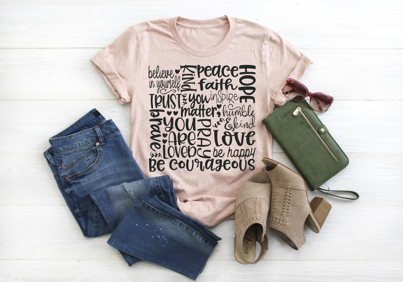 May include: A pink t-shirt with a black graphic design featuring the words "Hope", "Peace", "Faith", "Believe", "Trust", "You", "Matter", "Humble", "Brave", "Are", "Love", "Love", "Be Happy", and "Be Courageous".