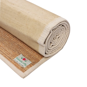 K&ouml;nnte beinhalten: Eine aufgerollte Yogamatte aus Naturfasern mit einer wei&szlig;en Baumwoll-Au&szlig;enschicht. Die Matte hat ein Etikett mit der Aufschrift "Abhineilkrafts Eat Pray Love Shop".
