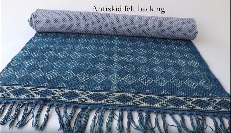 May include: A blue and white patterned rug with fringe on the ends. The rug has an anti-skid felt backing.