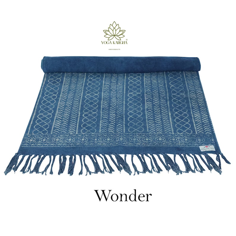 May include: A blue cotton yoga mat with a white geometric pattern and fringe. The mat is rolled up and has a label that says "Yoga Karcha". The text "Wonder" is printed below the mat.