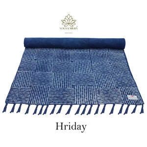 May include: A blue and white striped cotton yoga mat with tassels. The mat is rolled up and has a label that says "Yoga Karigha". The mat is called "Hriday".