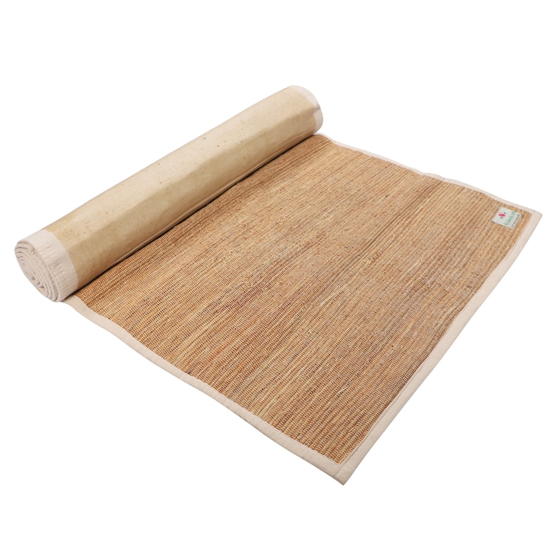 K&ouml;nnte beinhalten: Eine zusammengerollte Yogamatte aus Naturfasern mit wei&szlig;em Rand. Die Matte besteht aus gewebtem Stroh und ist f&uuml;r die Verwendung auf dem Boden konzipiert.