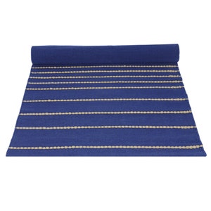 May include: A blue and cream striped rug with a woven texture. The rug is rolled up.
