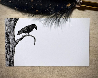 May include: A black and white illustration of a raven perched on a tree branch. The raven is facing left, with a detailed depiction of its feathers. The tree is also black and white, with a textured bark. A black feather pen is in the background.