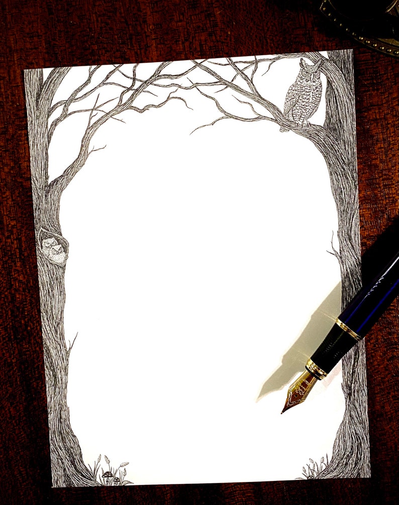 May include: A black and white pen and ink drawing of a tree with an owl perched on a branch. The drawing is on a white sheet of paper with a brown wooden background.
