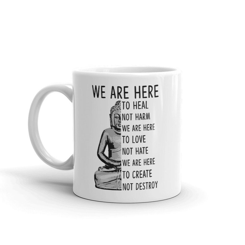 May include: White ceramic coffee mug with a black and white image of Buddha and the text "WE ARE HERE TO HEAL NOT HARM WE ARE HERE TO LOVE NOT HATE WE ARE HERE TO CREATE NOT DESTROY".