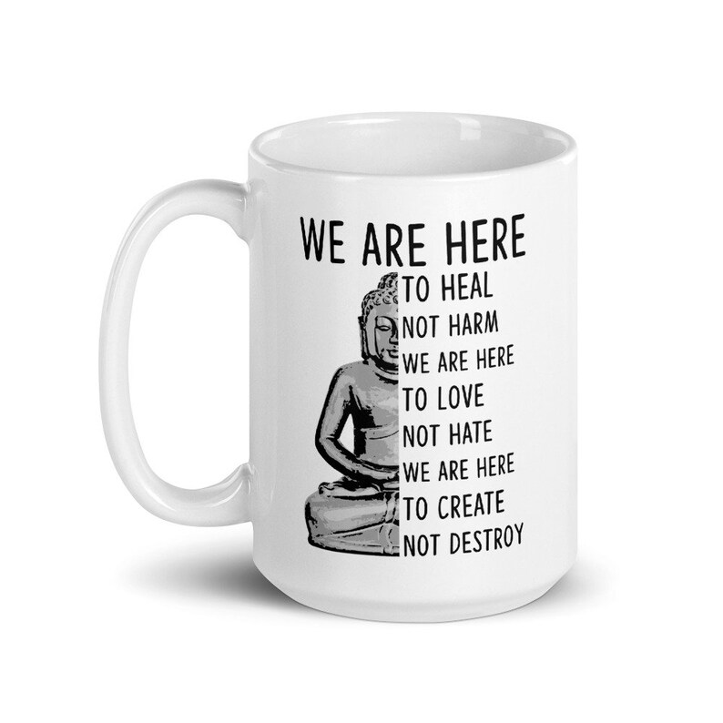 May include: White ceramic mug with a black and white image of Buddha and the text "We are here to heal not harm, we are here to love not hate, we are here to create not destroy."