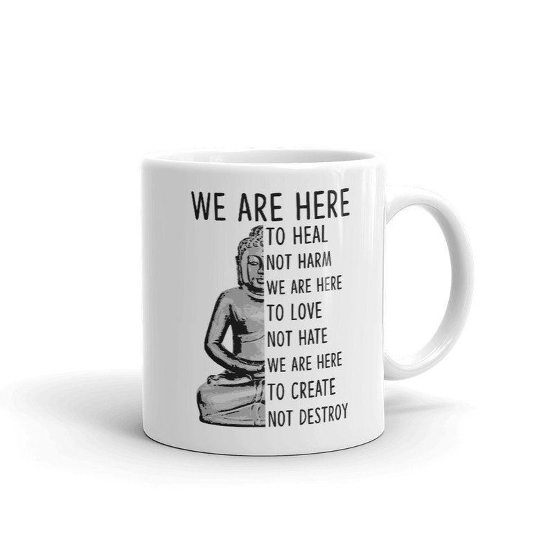 May include: White ceramic mug with a black and white image of Buddha and the text "WE ARE HERE TO HEAL NOT HARM WE ARE HERE TO LOVE NOT HATE WE ARE HERE TO CREATE NOT DESTROY".