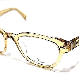Puede incluir: Gafas de color ámbar claro con montura de ojo de gato. Las lentes son transparentes y la marca SERAPHIN está impresa en la lente inferior izquierda. Las patillas son de un tono ámbar más claro.