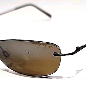 May include: Black rimless sunglasses with polarized lenses. The lenses have a gradient tint, transitioning from a darker shade at the top to a lighter shade at the bottom. The text "POLARIZED" is printed on the lens.