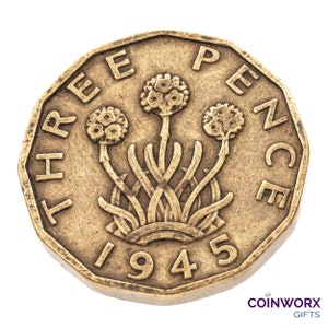 May include: A gold-coloured three pence coin from 1945 with the words "THREE PENCE" around the edge and a floral design in the centre.