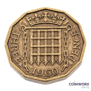 May include: A gold-coloured three pence coin from the United Kingdom, featuring a crown and a gate with a chain, and the year 1960.