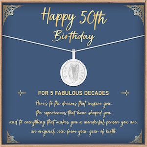 May include: A silver pendant necklace with a coin featuring a harp design, presented on a blue card with gold text that reads "Happy 50th Birthday." The card includes the text "For 5 Fabulous Decades."